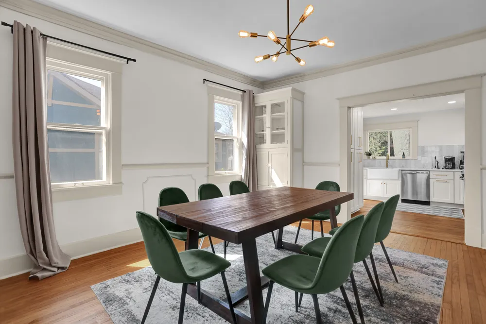 The dining room with a long wooden table and green chairs.