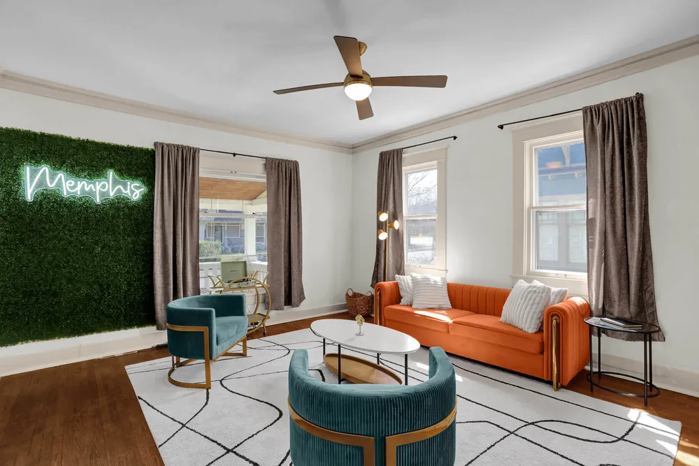 The living room with an orange sofa and teal chairs.